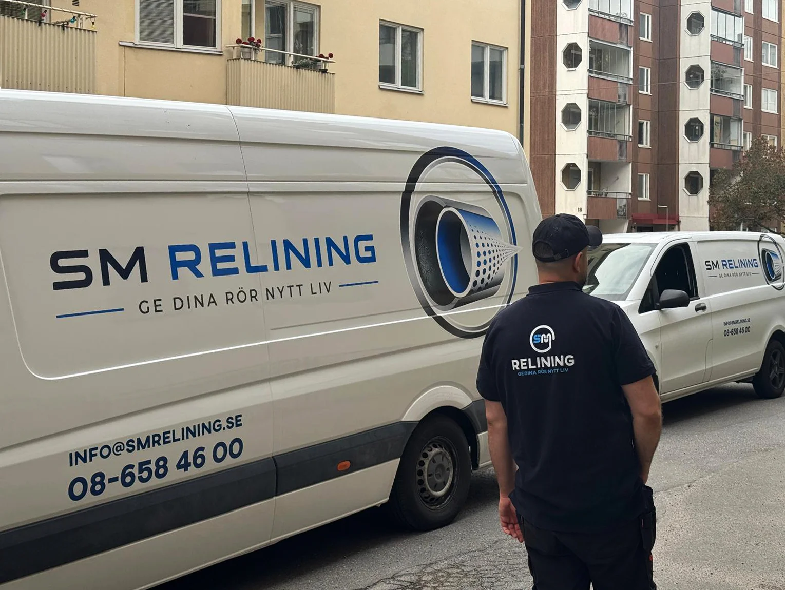 En SM Relining-tekniker står framför två vita servicebilar.